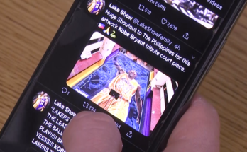 A hand holding a phone displaying Twitter